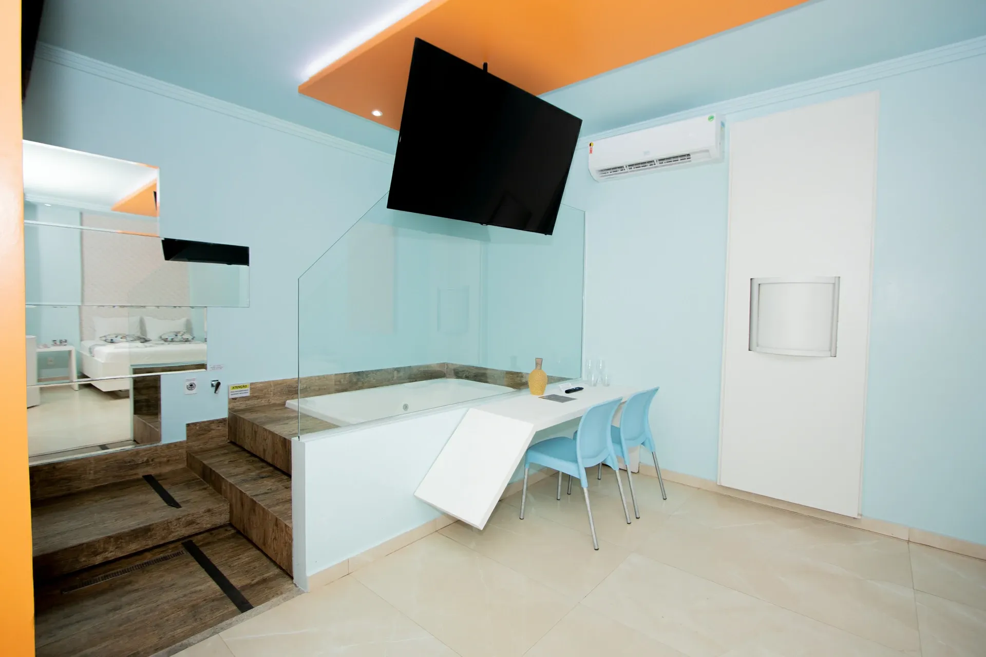 Suíte Hidro Plus do Motel Opium em Boa Vista: Área da hidromassagem da suíte: banheira embutida em deque de porcelanato amadeirado elevado, atrás de divisór