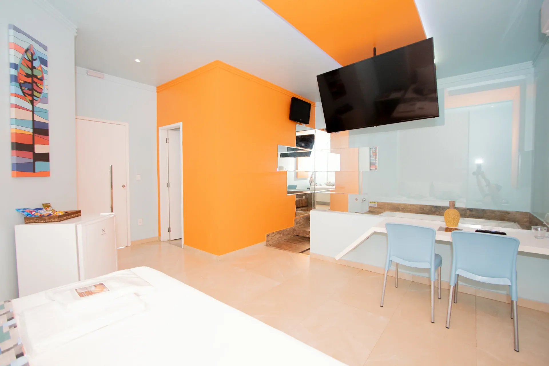Suíte Hidro Plus do Motel Opium em Boa Vista: Close da banheira de hidromassagem em primeiro plano, com jatos aparentes, sobre plataforma de porcelanato ama