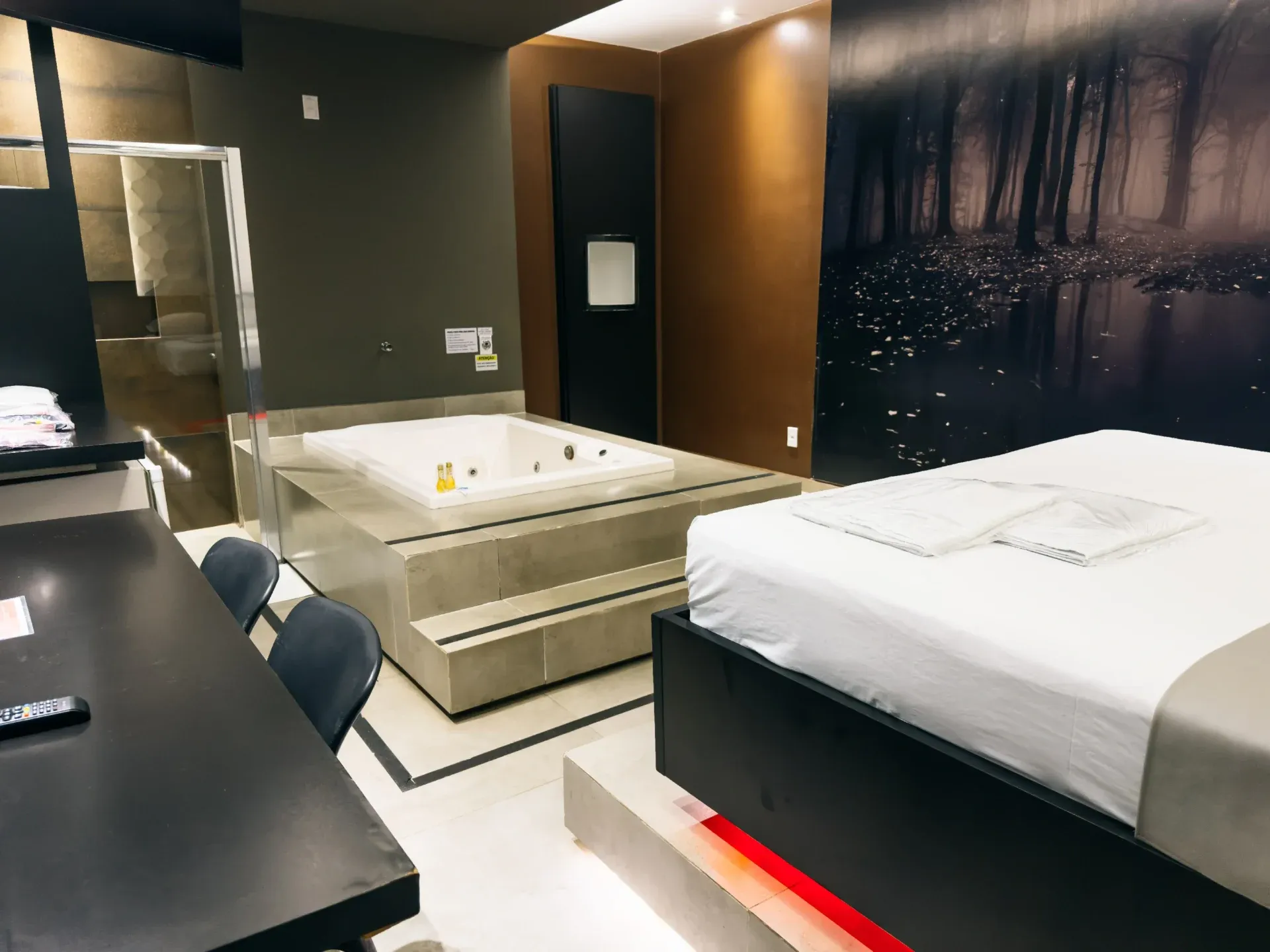Suíte Luxo Hidro do Motel Opium em Boa Vista: Suíte com hidromassagem: banheira quadrada branca dupla sobre plataforma elevada de porcelanato bege com degra