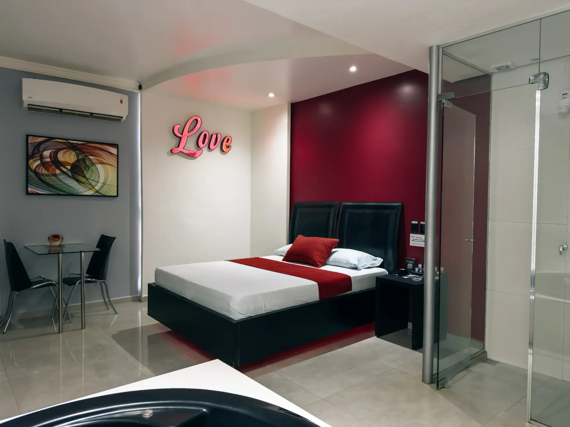 Suíte Luxo Hidro do Motel Opium em Boa Vista: Suíte temática romântica: letreiro decorativo rosa 'Love' na parede off-white, parede de destaque bordô atrás 