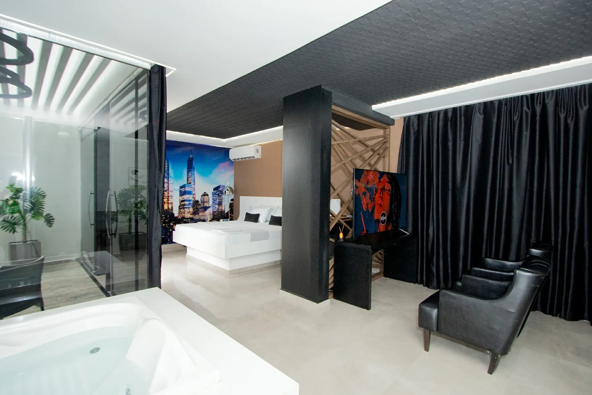 Suíte Opium do Motel Opium em Boa Vista: Outro ângulo da mesma suíte master: cama branca flutuante centralizada sob mural do skyline de NY, box de vidr