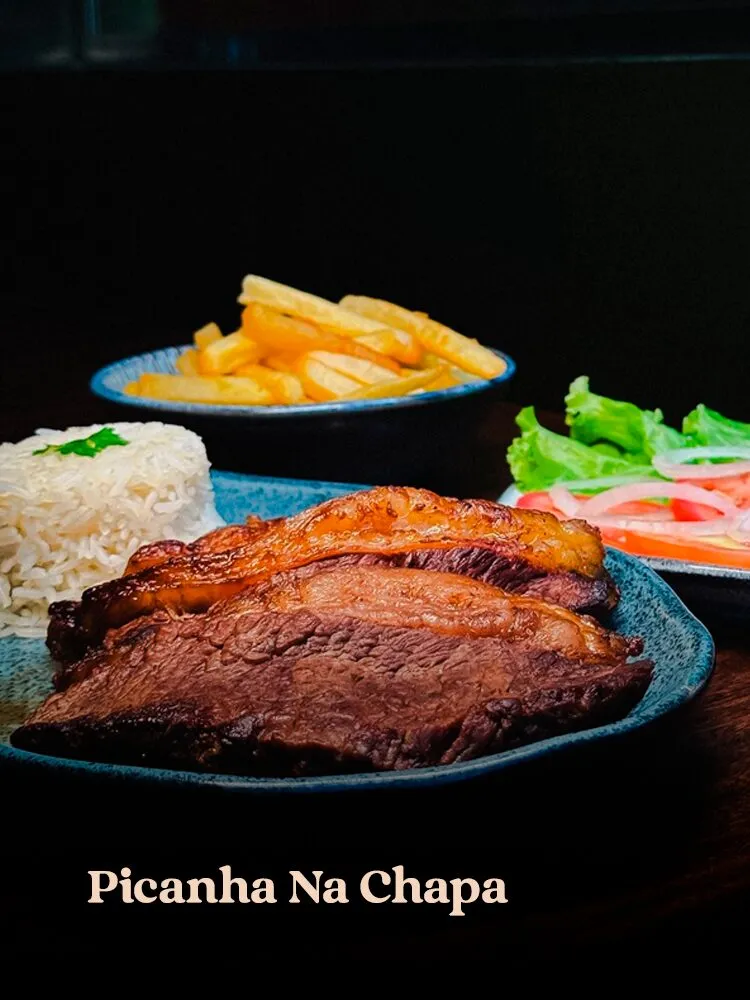 Fatias de picanha grelhada com capa de gordura dourada em prato azul mesclado, acompanhadas de arroz branco, s · cardápio do Motel Opium