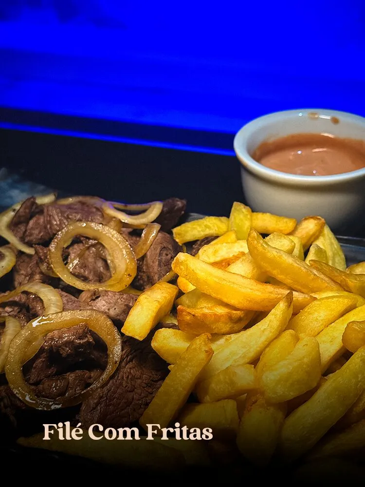 Tiras de filé com anéis de cebola ao lado de porção generosa de fritas e ramekin de molho rosé, com forte luz · cardápio do Motel Opium