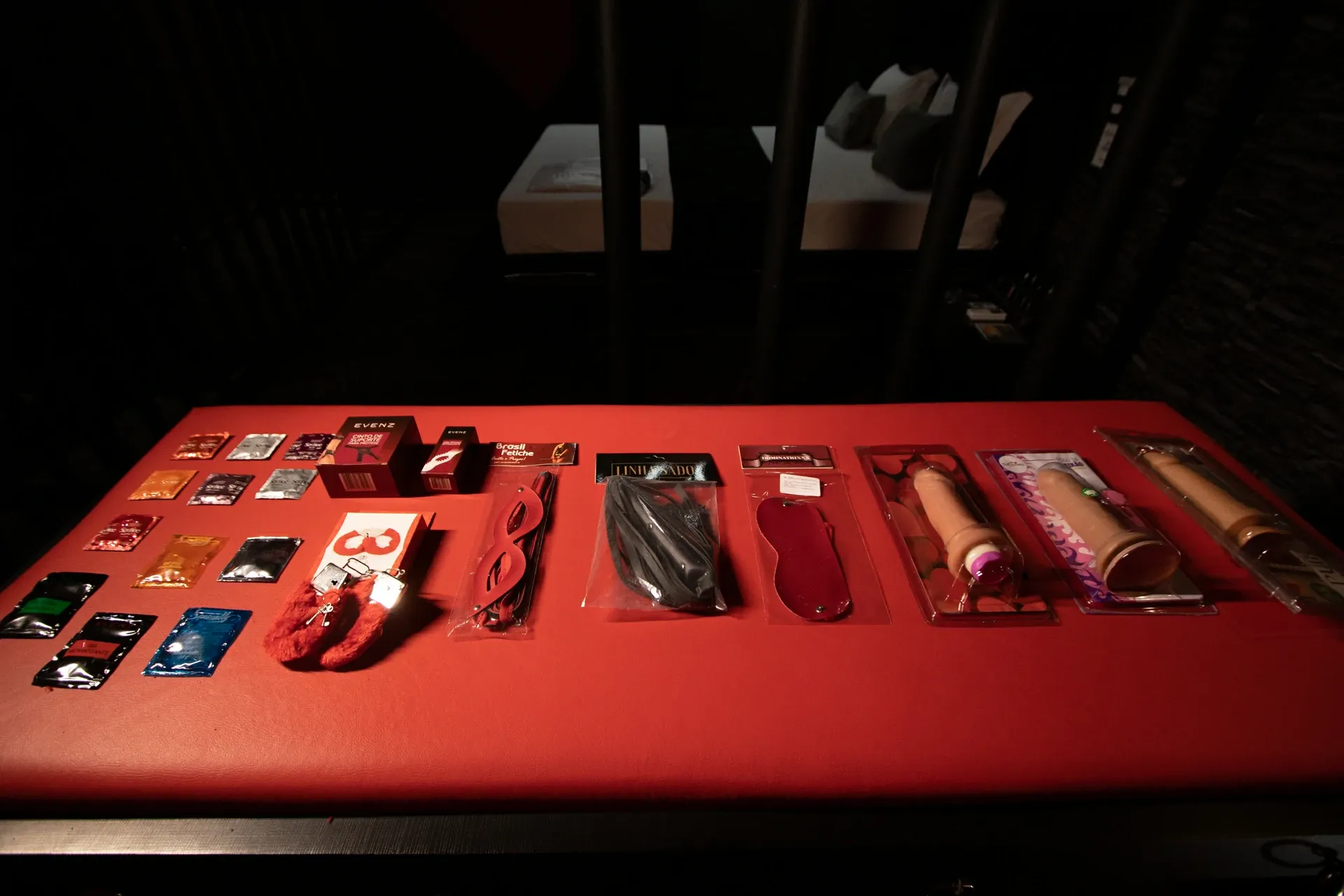 Suíte Sado do Motel Opium em Boa Vista: Still life low-key do 'menu erótico' da suíte Sado: sobre o banco acolchoado vermelho estão dispostos sachês d
