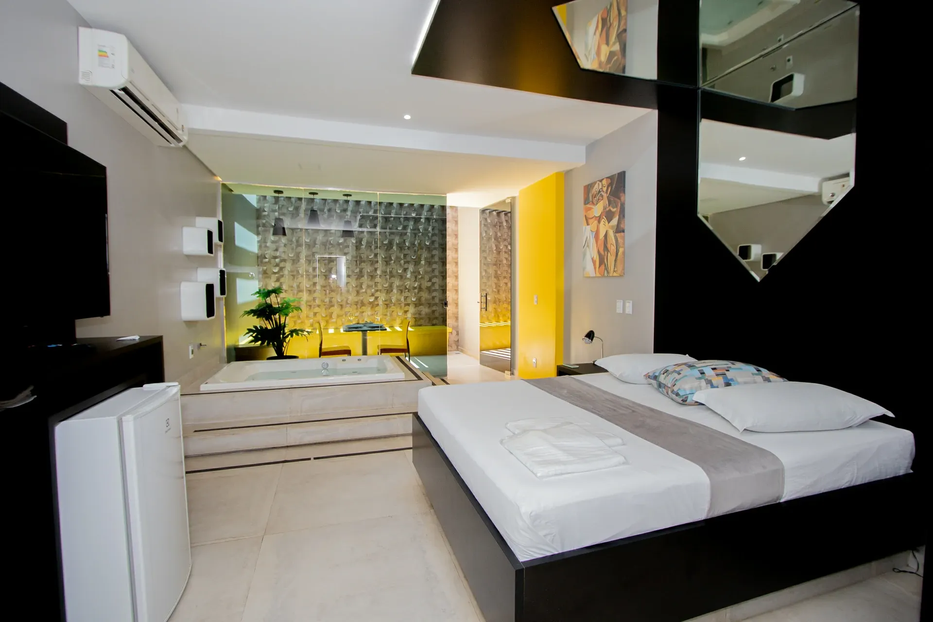 Suíte VIP do Motel Opium em Boa Vista: Suíte moderna em preto, branco e amarelo: cama king com base preta e roupa branca/cinza, banheira de hidromass