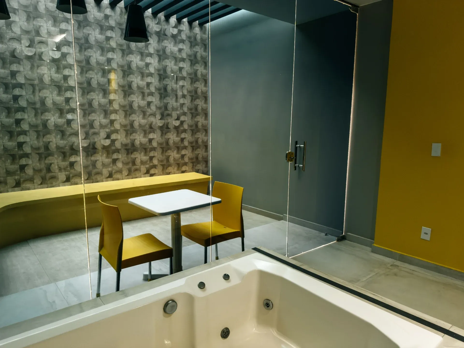 Suíte VIP do Motel Opium em Boa Vista: Detalhe da área de estar/hidro da suíte preto/amarelo: banheira de hidromassagem branca em primeiro plano atrá